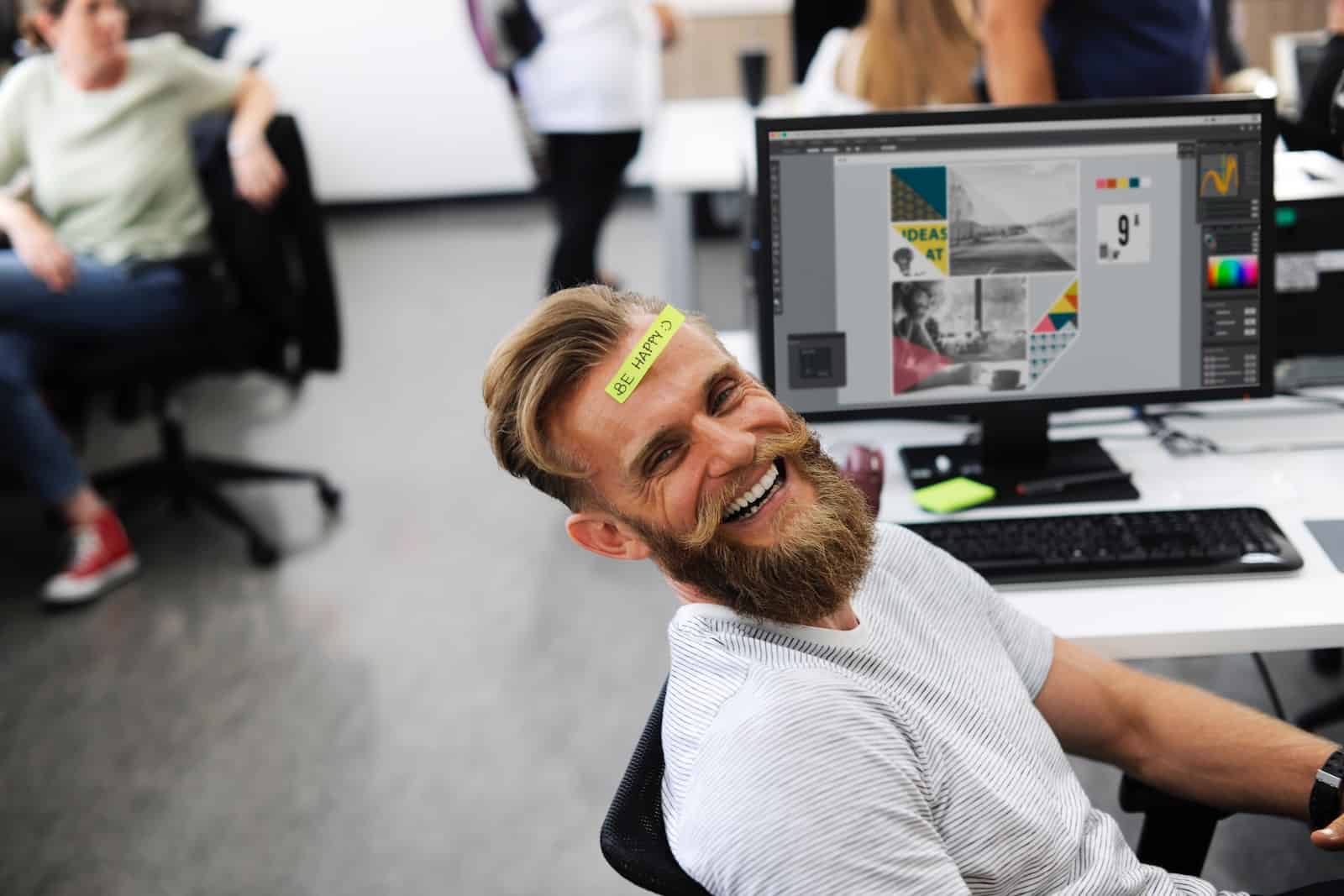 Why Getting Employee Buy In is worth your time a man sits at a swivel chair in an office and creates a sticker for his forehead that says be happy