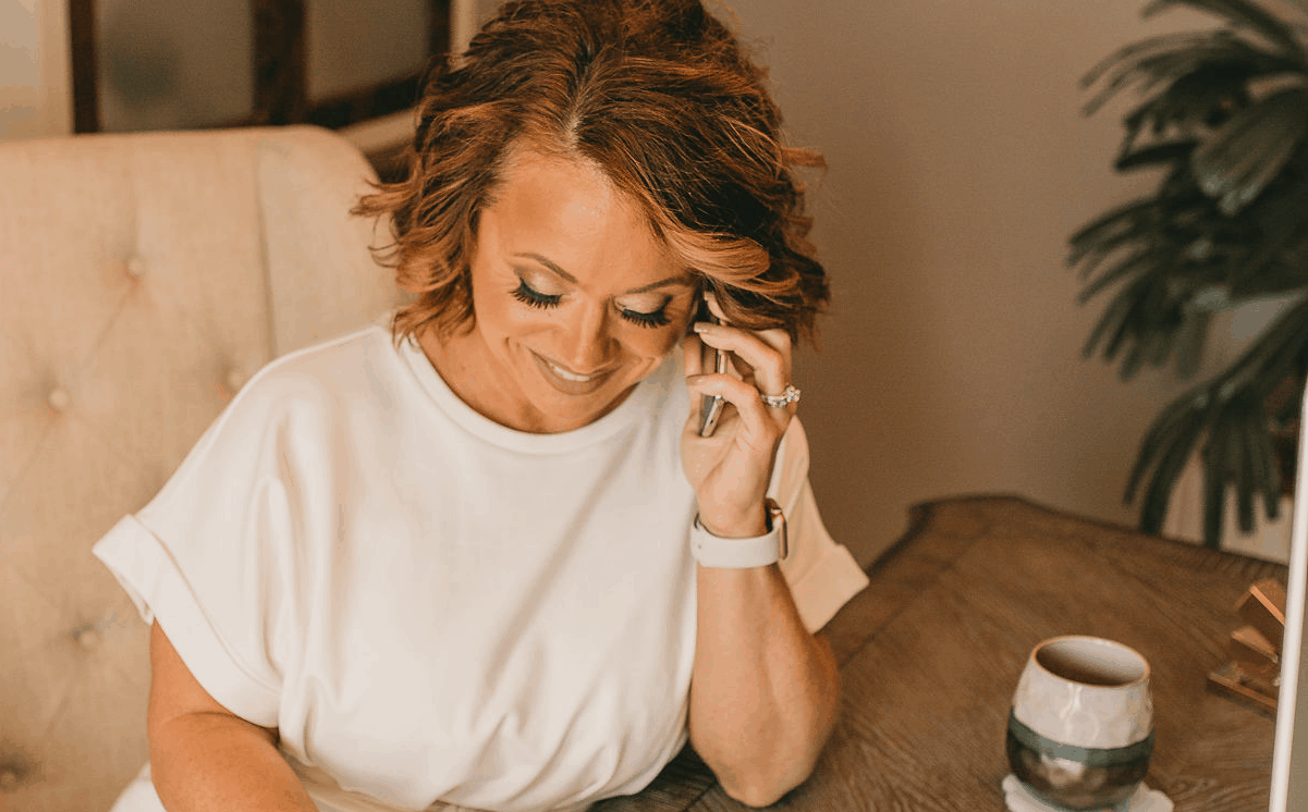 Kimberly Fulwood Owner of KF-Strategies answers a business phone call at her desk next to a cup of coffee